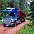 Scania kravas automašīna pārvadā grants pa meža ceļu